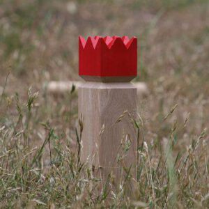 Kubb König mit roter Krone auf Wiese